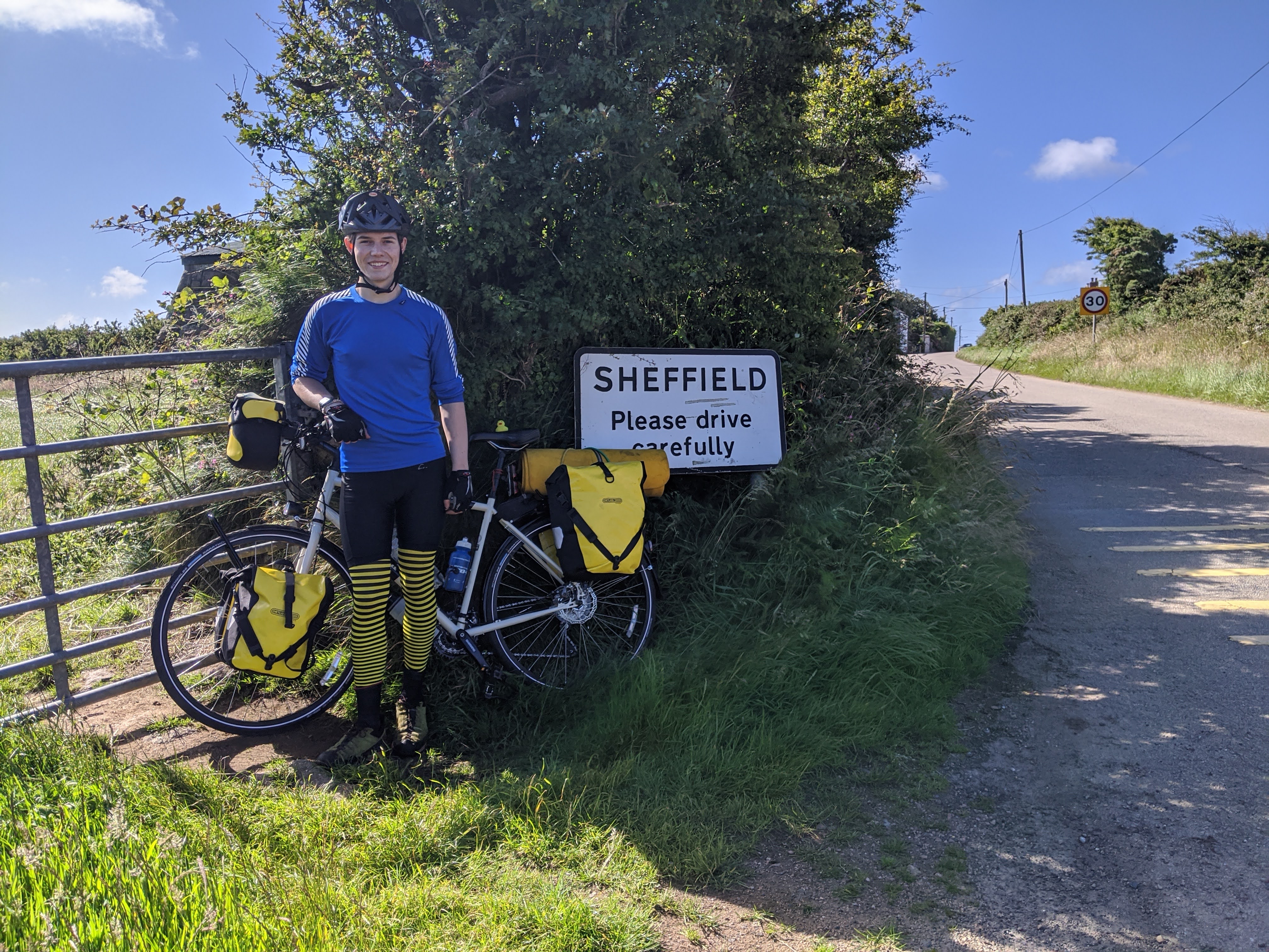 Myself and the bike next to a Sheffield signpost